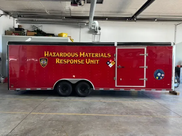 Red hazardous materials response unit truck parked in fire station garage bay